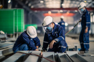Workers assembling steel components inside a modular home manufacturing facility · Master Modular Homes & Granny Flat